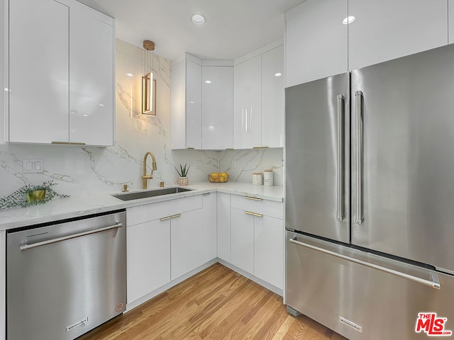 kitchen with stainless steel appliances, sink, white cabinets, and light hardwood / wood-style floors