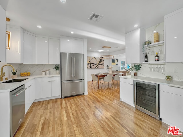 kitchen featuring sink, stainless steel appliances, beverage cooler, and white cabinets