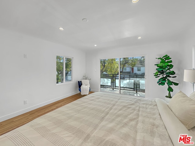 bedroom with multiple windows, access to outside, and light wood-type flooring