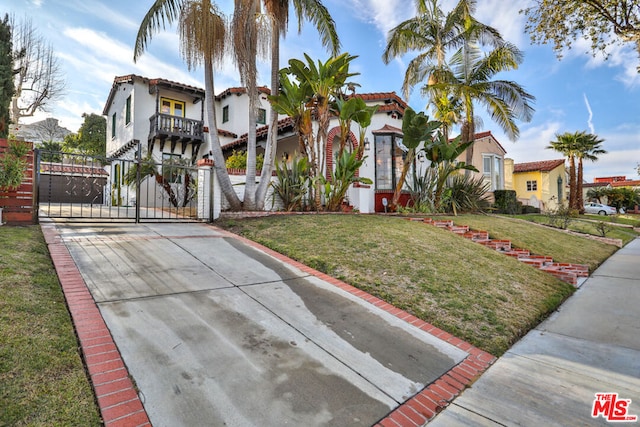 mediterranean / spanish-style home with a front lawn and a balcony