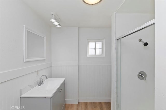 bathroom with hardwood / wood-style flooring, vanity, and a shower