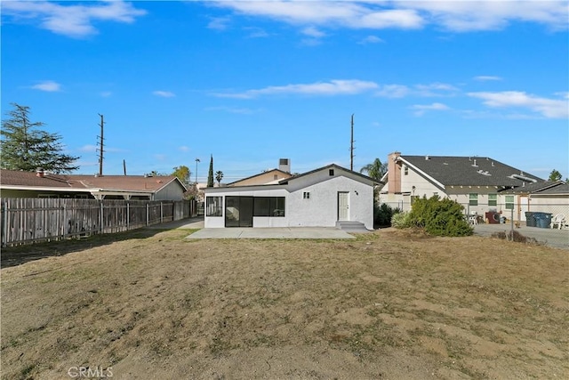 back of property with a sunroom, a yard, and a patio area