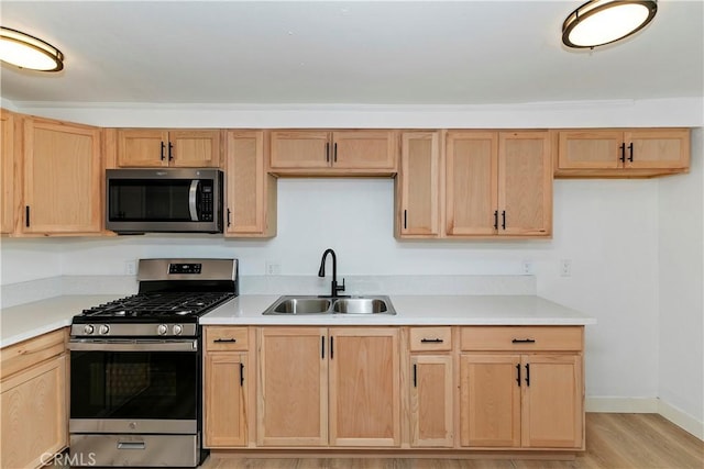 kitchen featuring appliances with stainless steel finishes, light brown cabinetry, sink, and light wood-type flooring