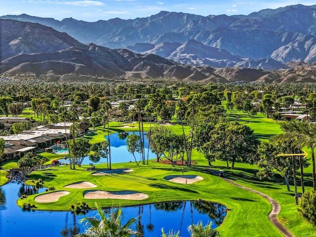 view of community with view of golf course, a lawn, and a water and mountain view