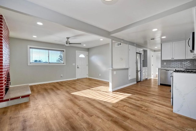 unfurnished living room featuring ceiling fan and light hardwood / wood-style flooring