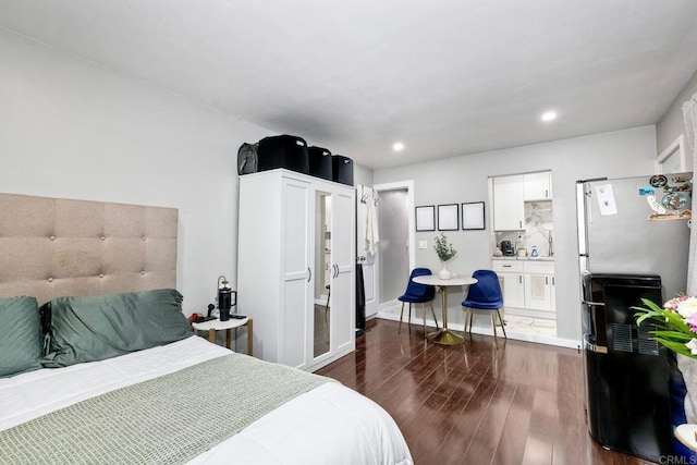 bedroom featuring stainless steel refrigerator and dark hardwood / wood-style flooring