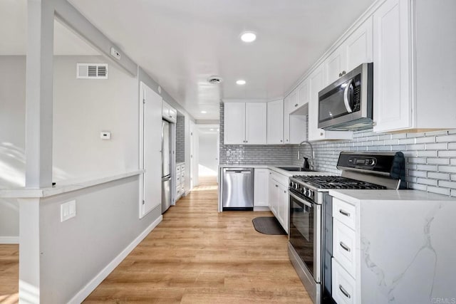 kitchen with white cabinetry, sink, decorative backsplash, light stone counters, and stainless steel appliances