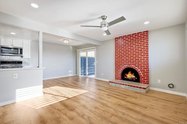 unfurnished living room with a brick fireplace, light hardwood / wood-style floors, and ceiling fan