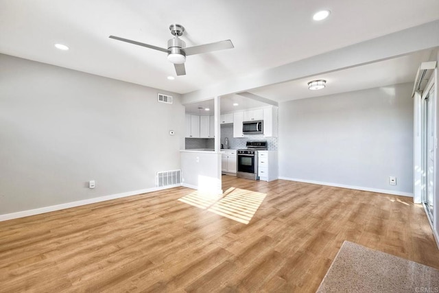 unfurnished living room with ceiling fan, sink, and light hardwood / wood-style flooring