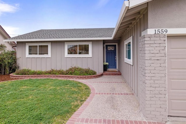 doorway to property with a garage and a lawn