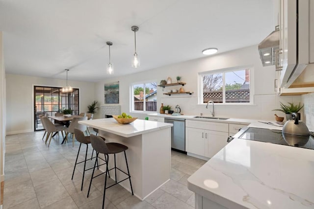 kitchen with pendant lighting, sink, white cabinetry, a center island, and stainless steel dishwasher