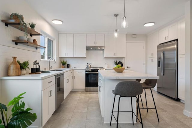 kitchen featuring sink, hanging light fixtures, appliances with stainless steel finishes, a kitchen island, and white cabinets