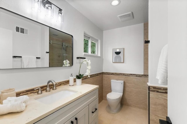 bathroom featuring tile walls, vanity, walk in shower, toilet, and tile patterned floors