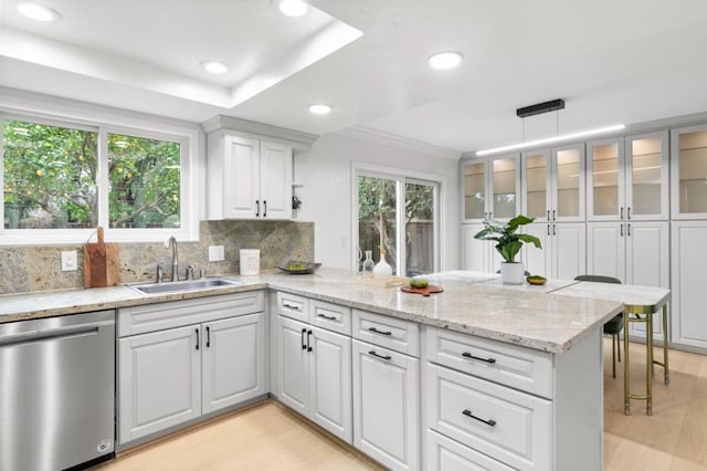 kitchen with sink, white cabinetry, dishwasher, kitchen peninsula, and pendant lighting