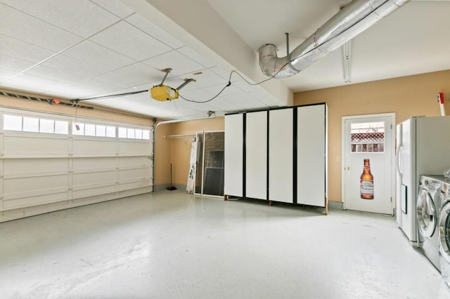 garage featuring white refrigerator, washing machine and clothes dryer, and a garage door opener