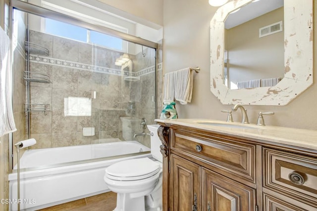 full bathroom featuring vanity, hardwood / wood-style flooring, enclosed tub / shower combo, and toilet