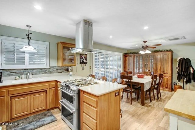 kitchen with island exhaust hood, kitchen peninsula, sink, and range with two ovens