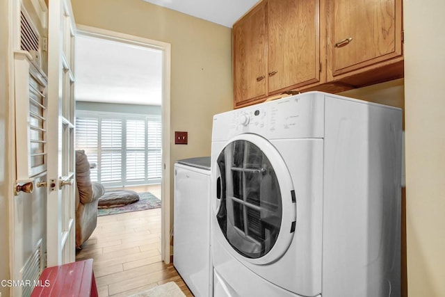 laundry room with cabinets, separate washer and dryer, and light wood-type flooring