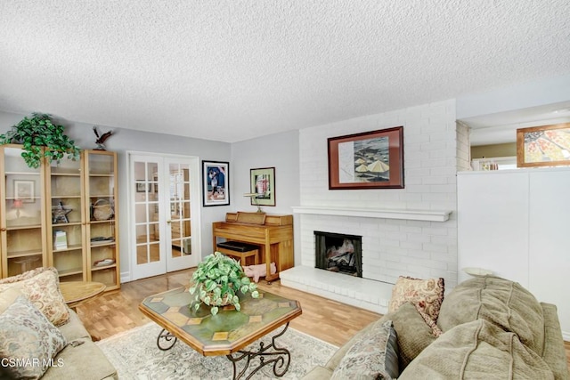 living room with french doors, hardwood / wood-style floors, a brick fireplace, and a textured ceiling