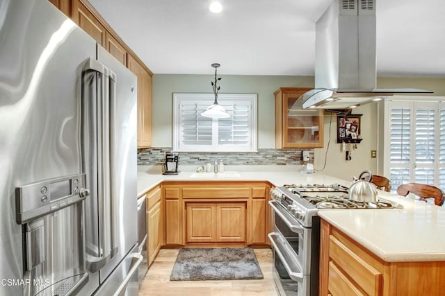 kitchen featuring sink, decorative light fixtures, kitchen peninsula, island exhaust hood, and stainless steel appliances