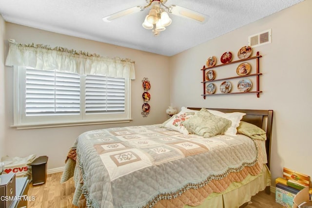 bedroom with hardwood / wood-style flooring, a textured ceiling, and ceiling fan