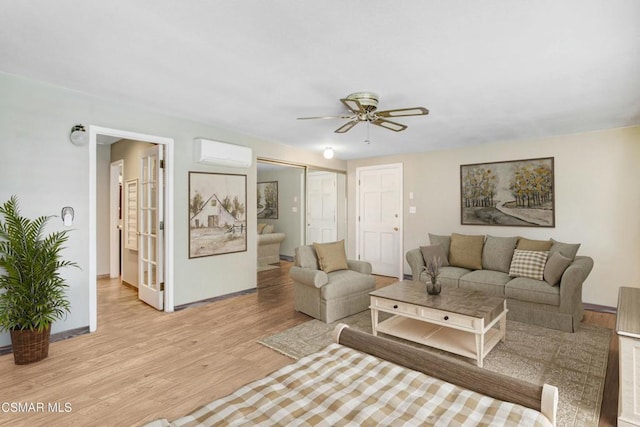 living room featuring ceiling fan, a wall mounted air conditioner, and light wood-type flooring