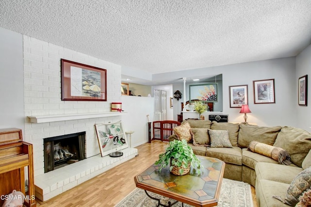 living room with wood-type flooring, a textured ceiling, and a fireplace