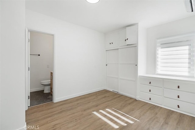 unfurnished bedroom featuring light hardwood / wood-style flooring, a closet, and ensuite bathroom