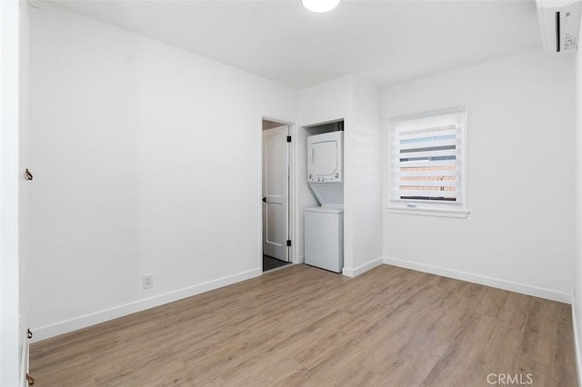 unfurnished bedroom featuring stacked washer and dryer and light hardwood / wood-style flooring