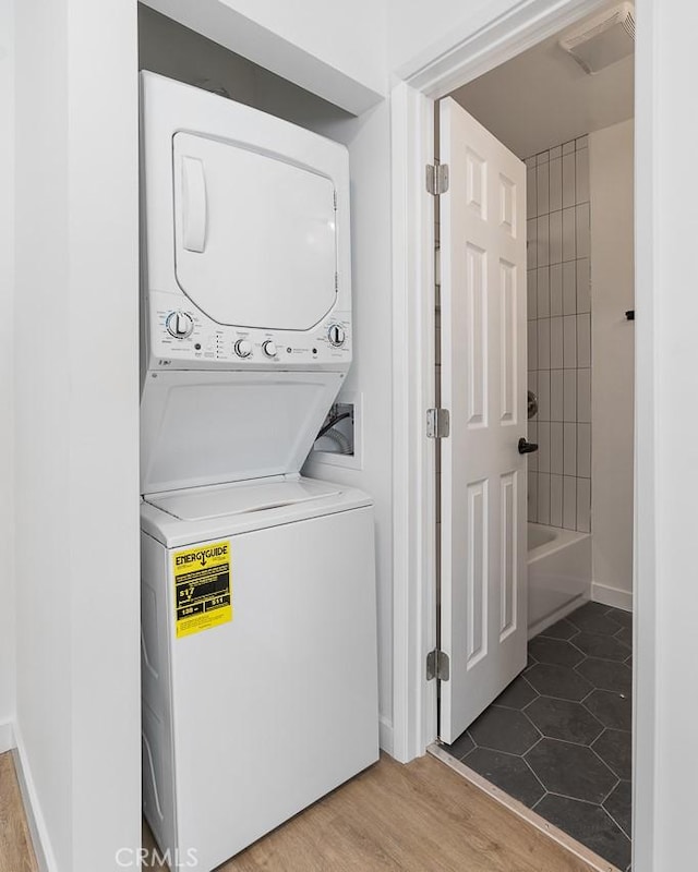 washroom featuring hardwood / wood-style flooring and stacked washing maching and dryer