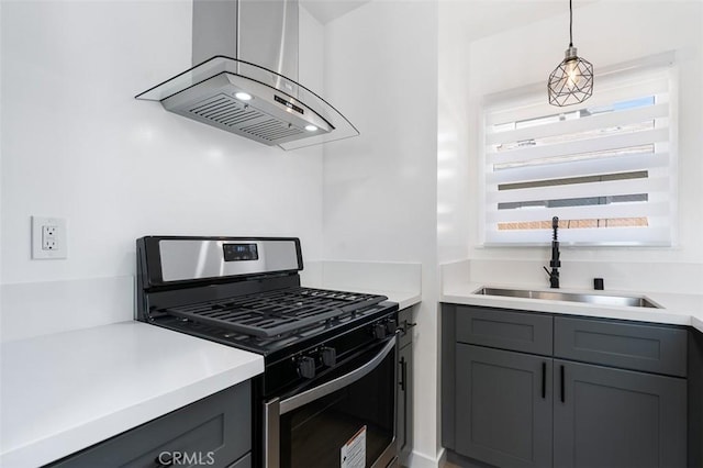 kitchen with stainless steel gas range, sink, island range hood, decorative light fixtures, and gray cabinets