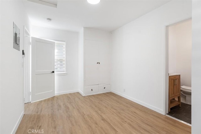 unfurnished bedroom with connected bathroom and light hardwood / wood-style flooring