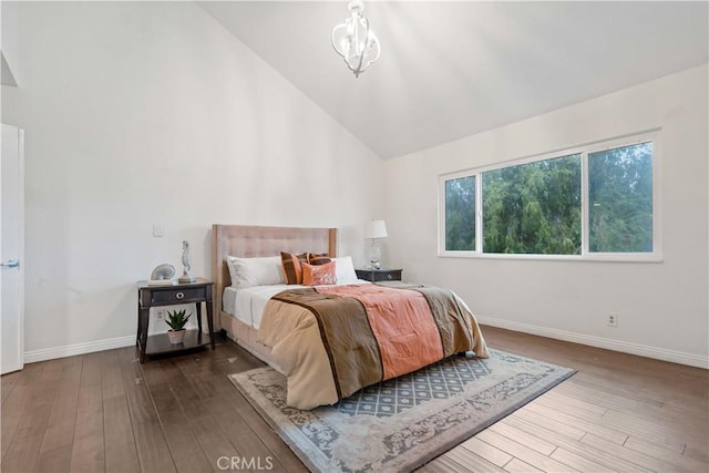 bedroom with an inviting chandelier, wood-type flooring, and high vaulted ceiling