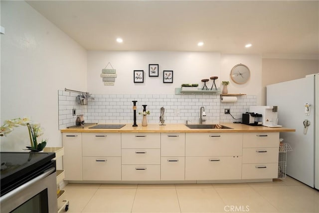 kitchen featuring sink, wooden counters, fridge, tasteful backsplash, and light tile patterned flooring