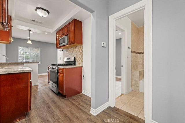 kitchen with sink, wood-type flooring, stainless steel appliances, and hanging light fixtures