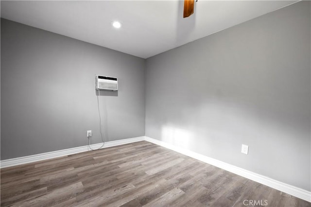 spare room featuring ceiling fan, wood-type flooring, and a wall mounted AC