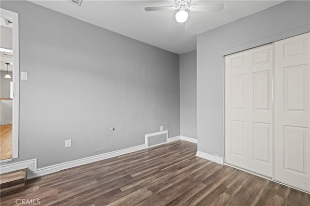 unfurnished bedroom with a closet, dark hardwood / wood-style floors, and ceiling fan