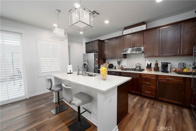 kitchen with pendant lighting, a kitchen bar, dark hardwood / wood-style floors, and an island with sink