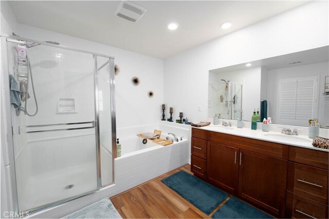 bathroom featuring vanity, hardwood / wood-style floors, and plus walk in shower