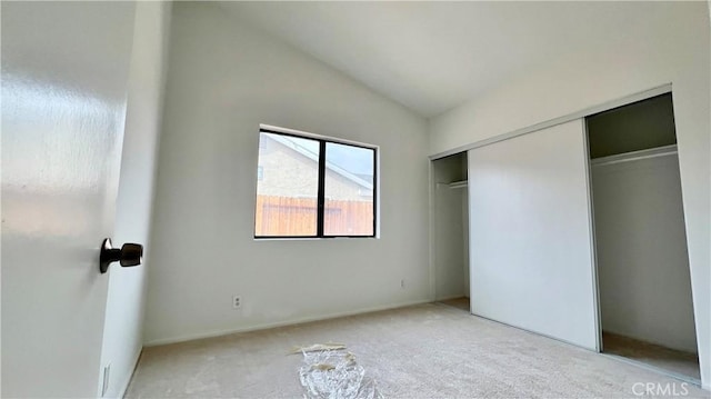 unfurnished bedroom with light carpet, vaulted ceiling, and a closet