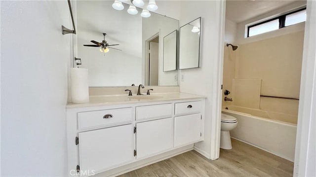 full bathroom with wood-type flooring, vanity,  shower combination, ceiling fan, and toilet