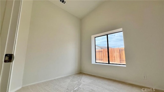 carpeted empty room with vaulted ceiling