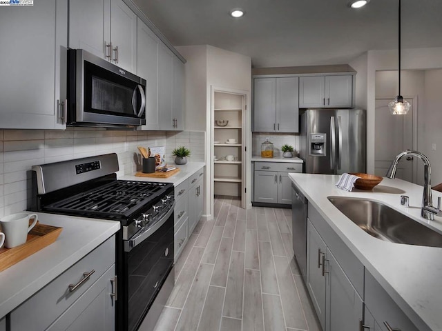 kitchen with gray cabinets, appliances with stainless steel finishes, sink, and decorative light fixtures