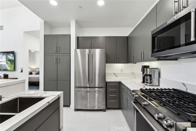 kitchen featuring appliances with stainless steel finishes, recessed lighting, gray cabinetry, and light stone countertops