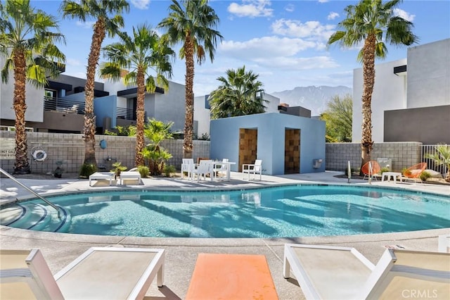 pool with a patio area, a mountain view, and fence