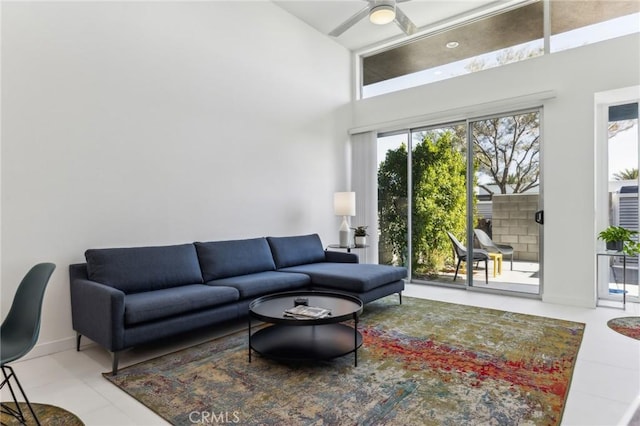 living area with ceiling fan and a high ceiling