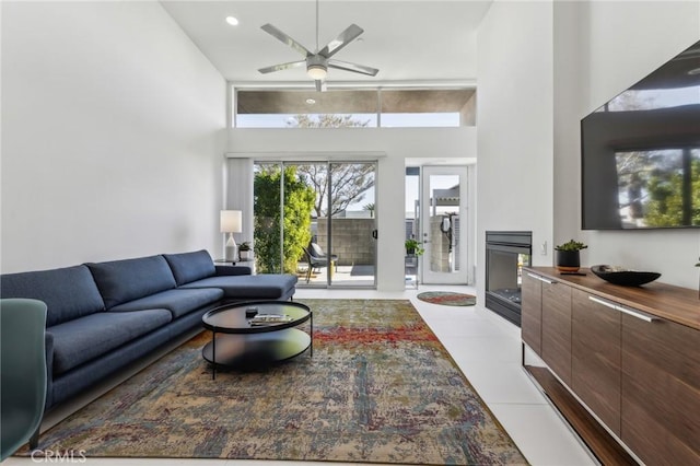 living room featuring light tile patterned floors, ceiling fan, a towering ceiling, and recessed lighting