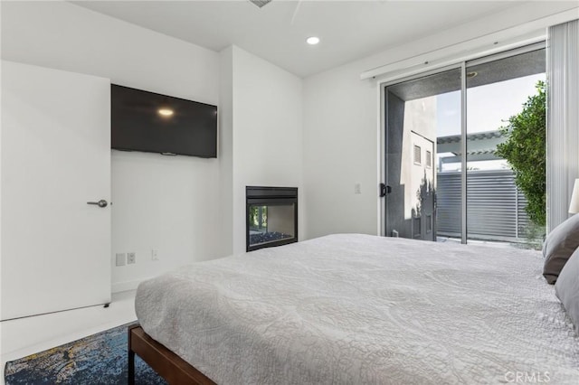 bedroom featuring recessed lighting, a glass covered fireplace, and access to exterior