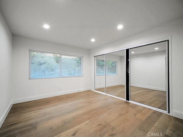 unfurnished bedroom with hardwood / wood-style floors and a closet