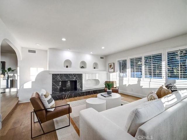 living room with a high end fireplace and wood-type flooring